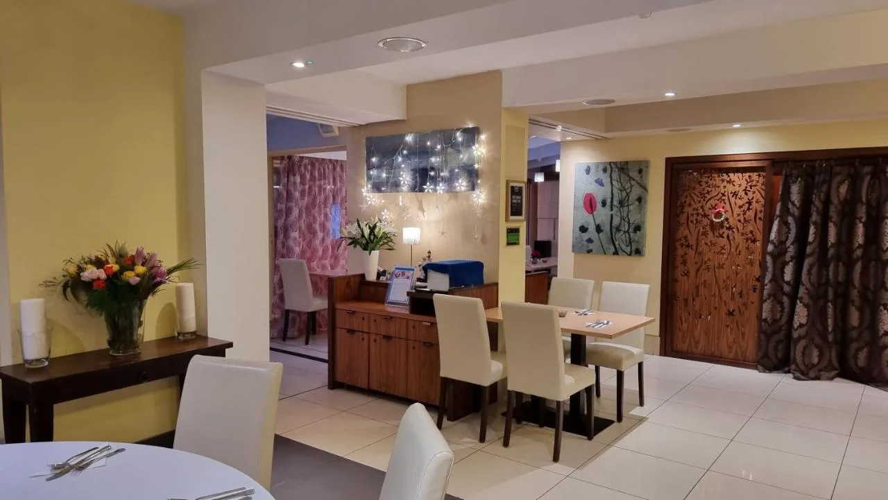 a dining room with a table and white chairs at The Park City Grand Plaza Kensington Hotel in London