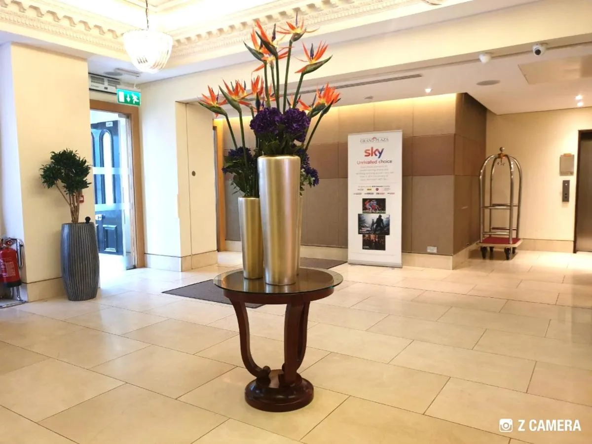 a vase with flowers on a table in a lobby at The Park City Grand Plaza Kensington Hotel in London