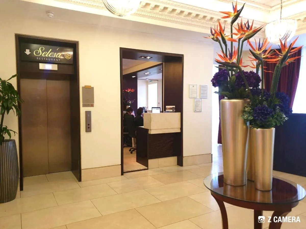 a lobby with vases of flowers on a table at The Park City Grand Plaza Kensington Hotel in London