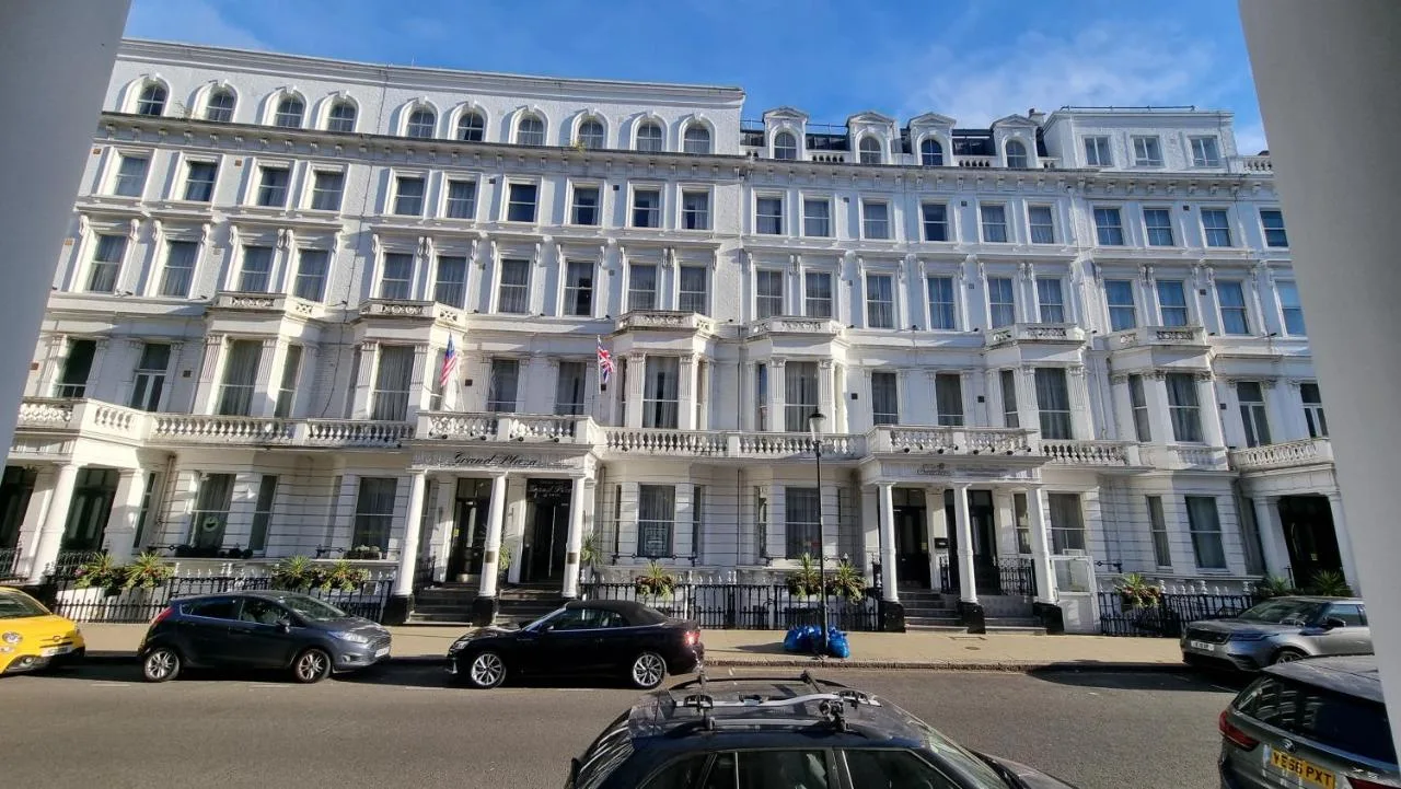 a large white building with cars parked in front of it at The Park City Grand Plaza Kensington Hotel in London